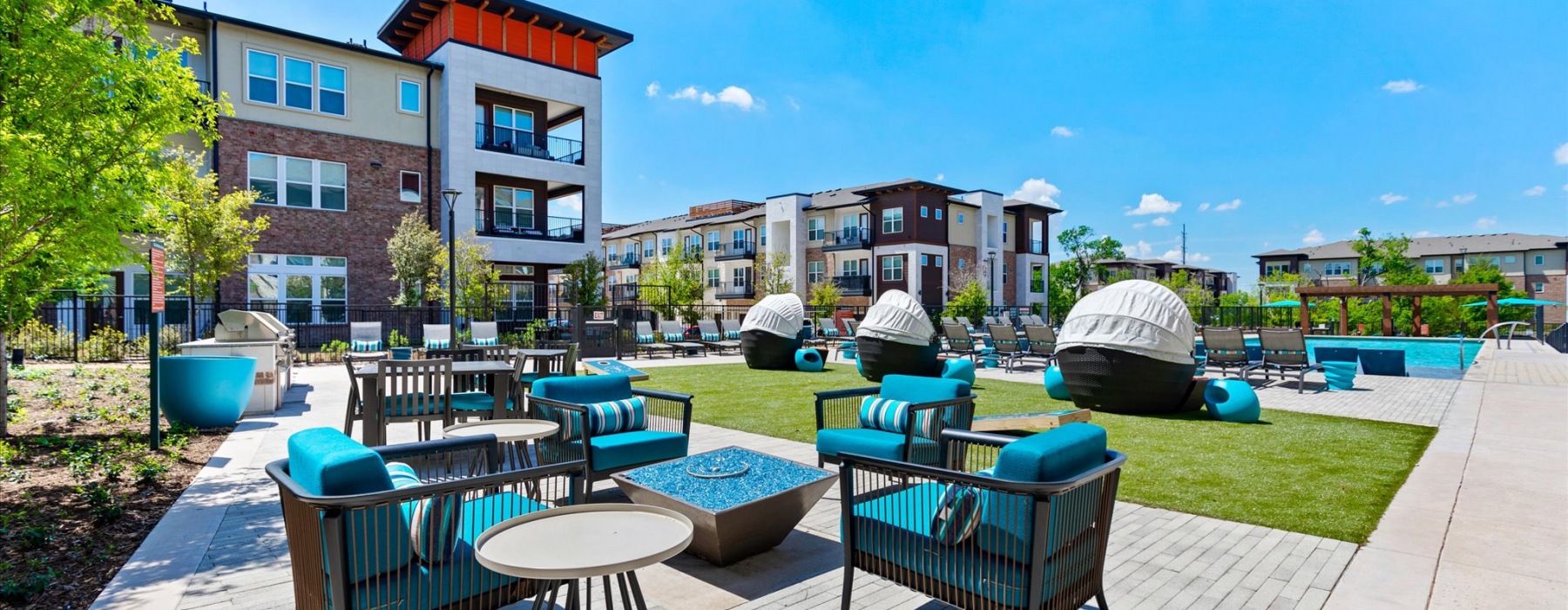 Outdoor lounge spaces with cabanas and a view of the pool at McKinney Terrace apartments in downtown McKinney, TX